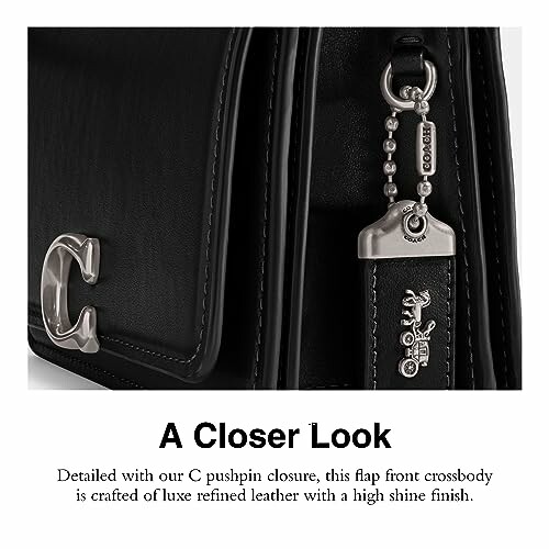 Close-up of a luxury leather crossbody bag with C pushpin closure and silver accents.