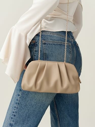 Woman in jeans with a beige clutch bag.