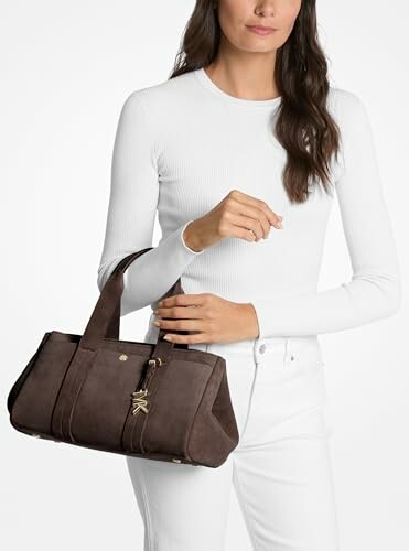 Woman in white outfit holding a brown handbag.